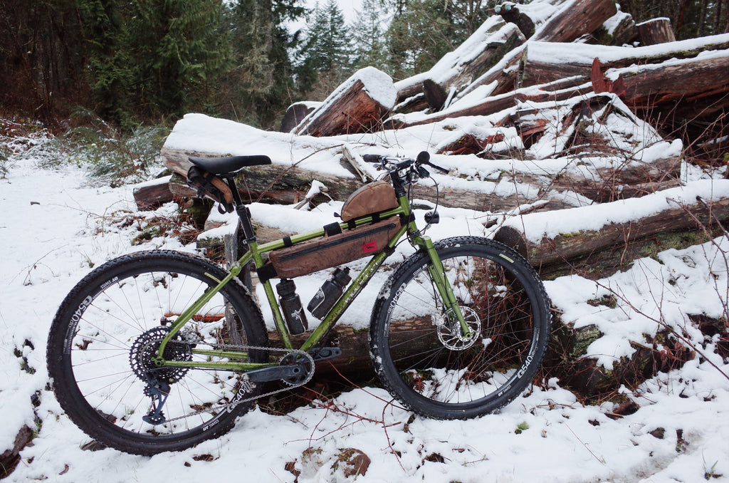 velo orange piolet in snow with tan bikepacking bags