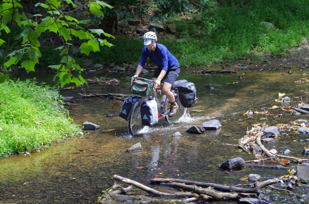 velo orange bike crossing a stream with fully loaded panniers