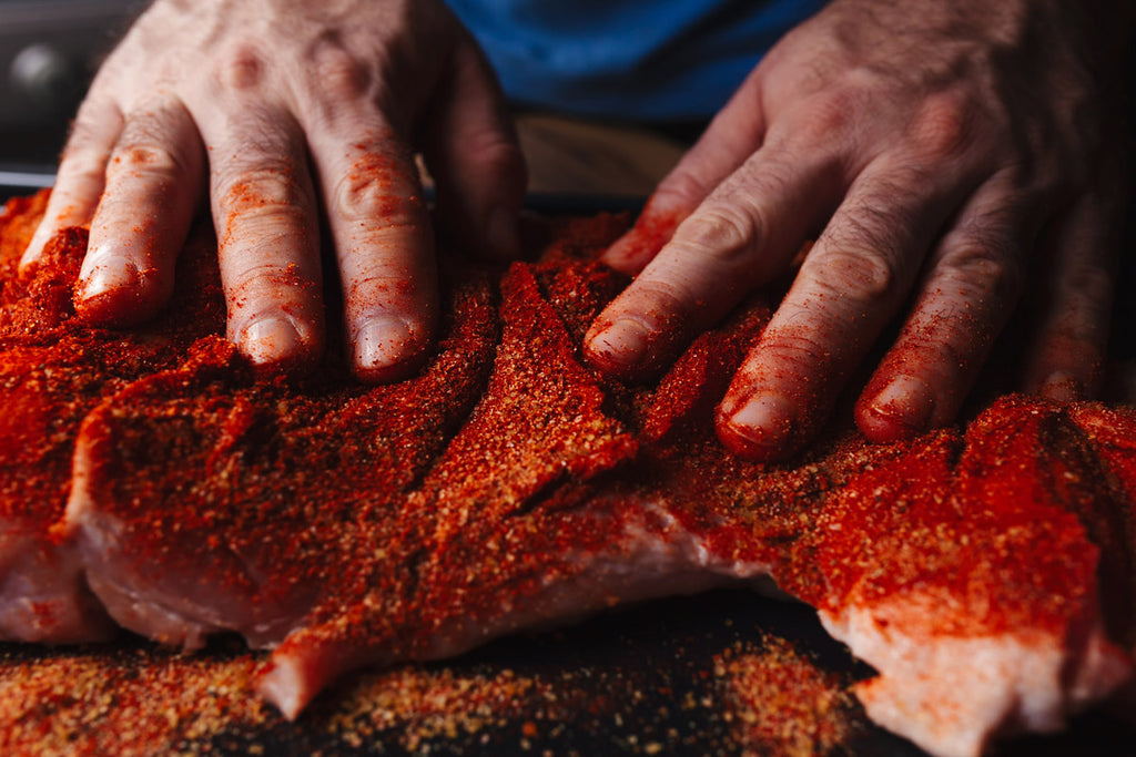 man massaging rub into meat