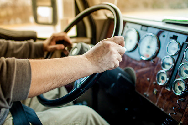 Delivery truck driver with hands on steering wheel in sitting position