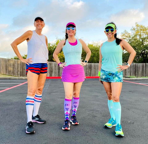 Three female runners wearing PRO Compression knee-high Marathon socks before a race.