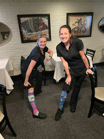 Two female restaurant servers wearing knee-high compression socks.