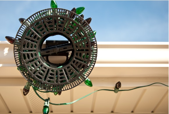 Install N Store Light storage reel hanging on rain gutter during Christmas light installation