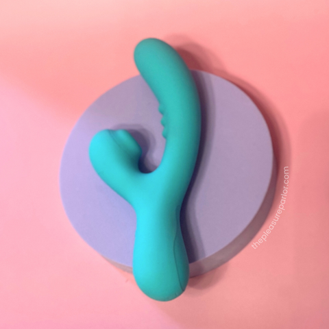 Rock Candy Toys Sugarotic Dual-Stimulation vibrator in aqua blue on a purple and pink background