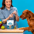 Woman hiding a pill in a Gulpz pill pocket while her dog watches and waits to eat the treat. 