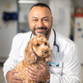 Veterinarian and Vetnique Founder Dr. James Bascharon wearing a lab coat while holding a small dog.