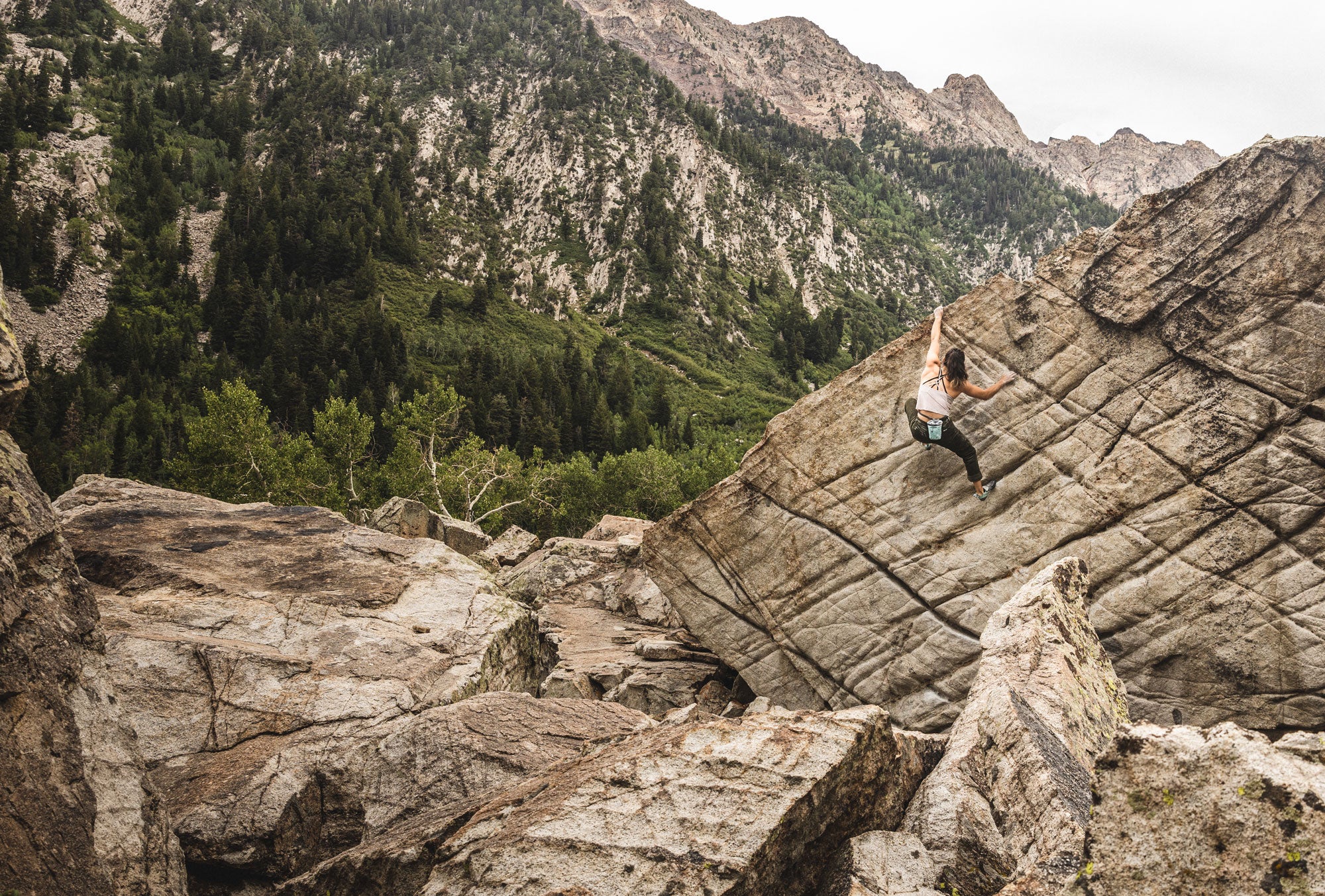 Quinn Mason summiting a boulder with exposed mountains in the background