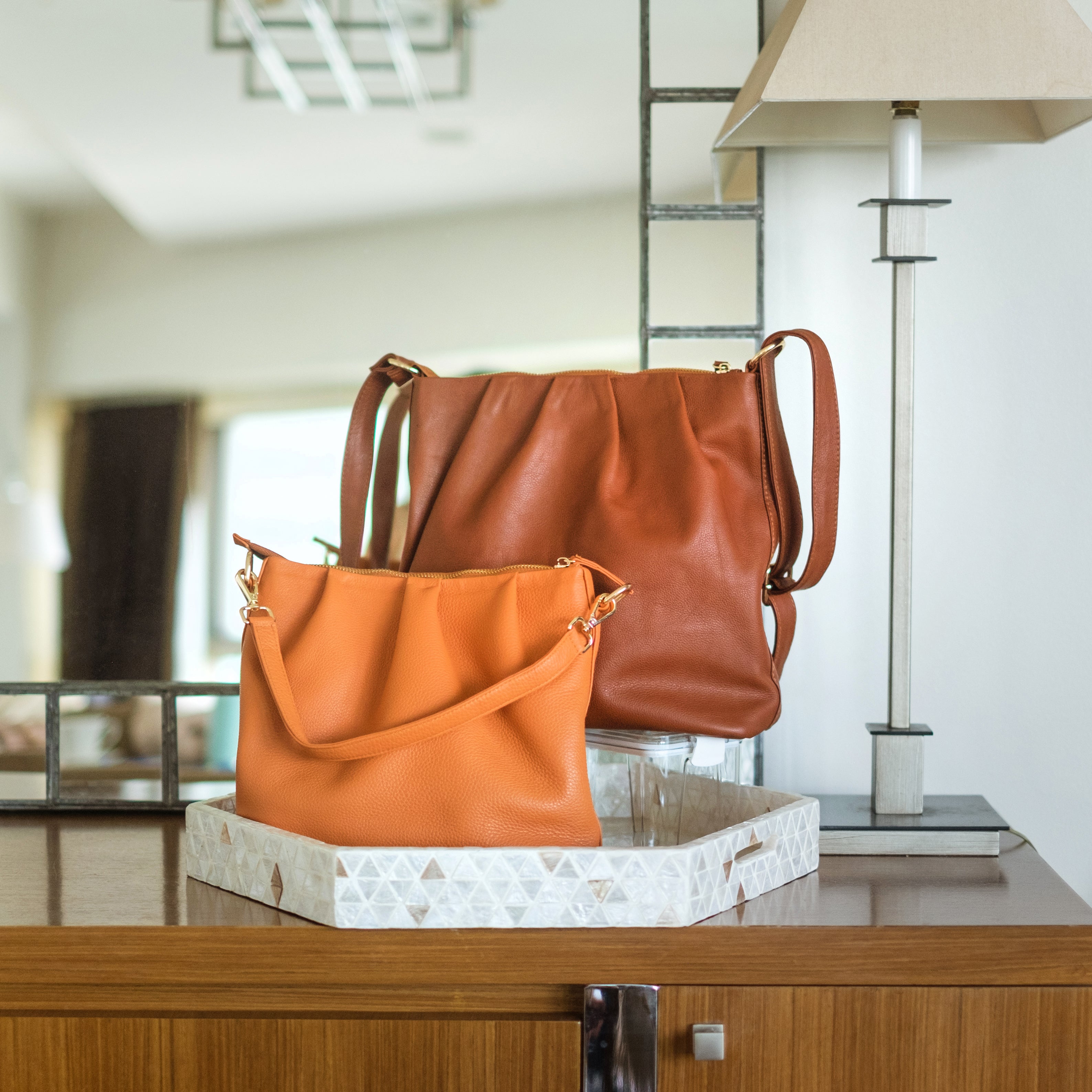 two bucket bags in apricot and rust colors displayed on a table