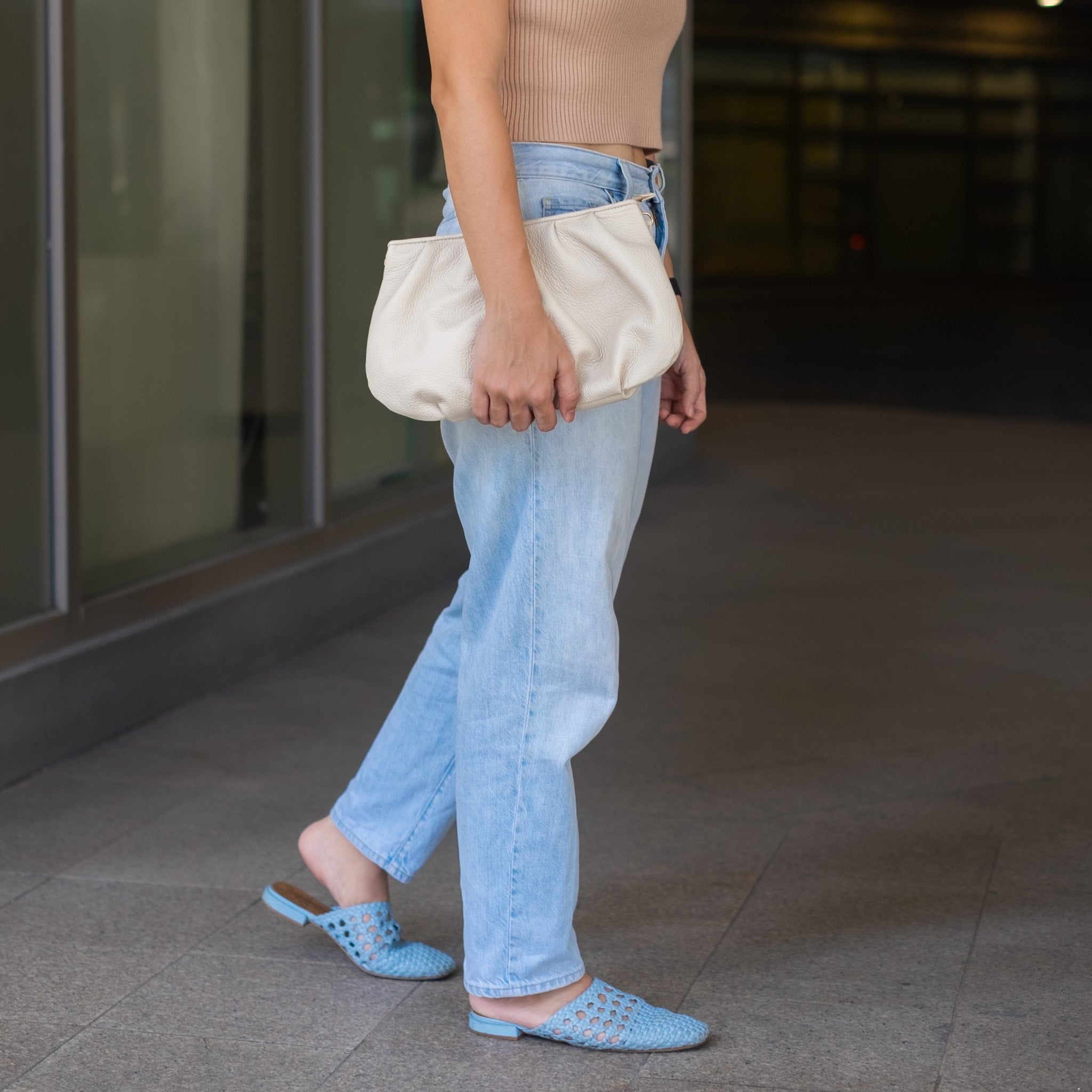 woman carrying an off-white clutch bag