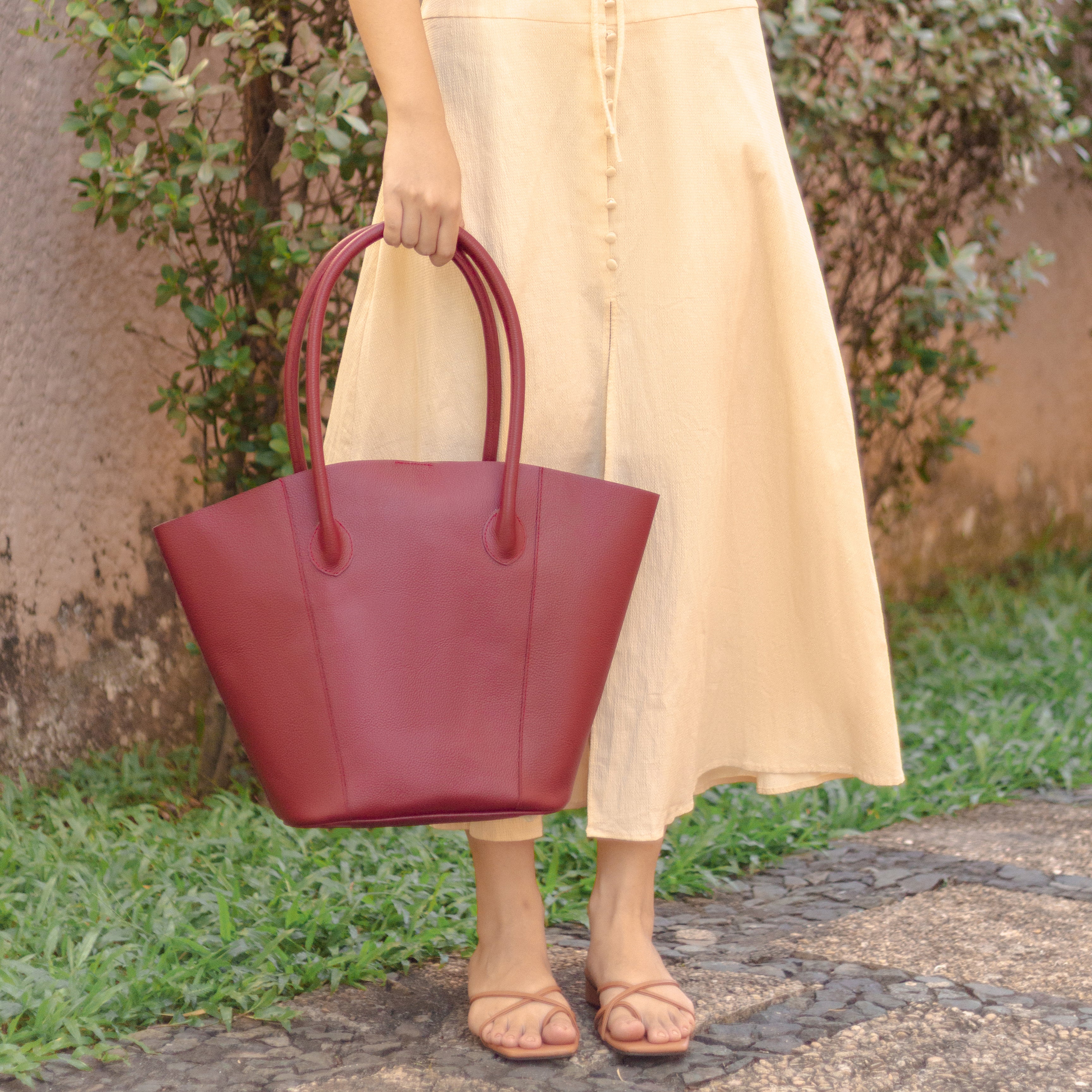 woman in peach dress holding a florence bucket tote bag in wine