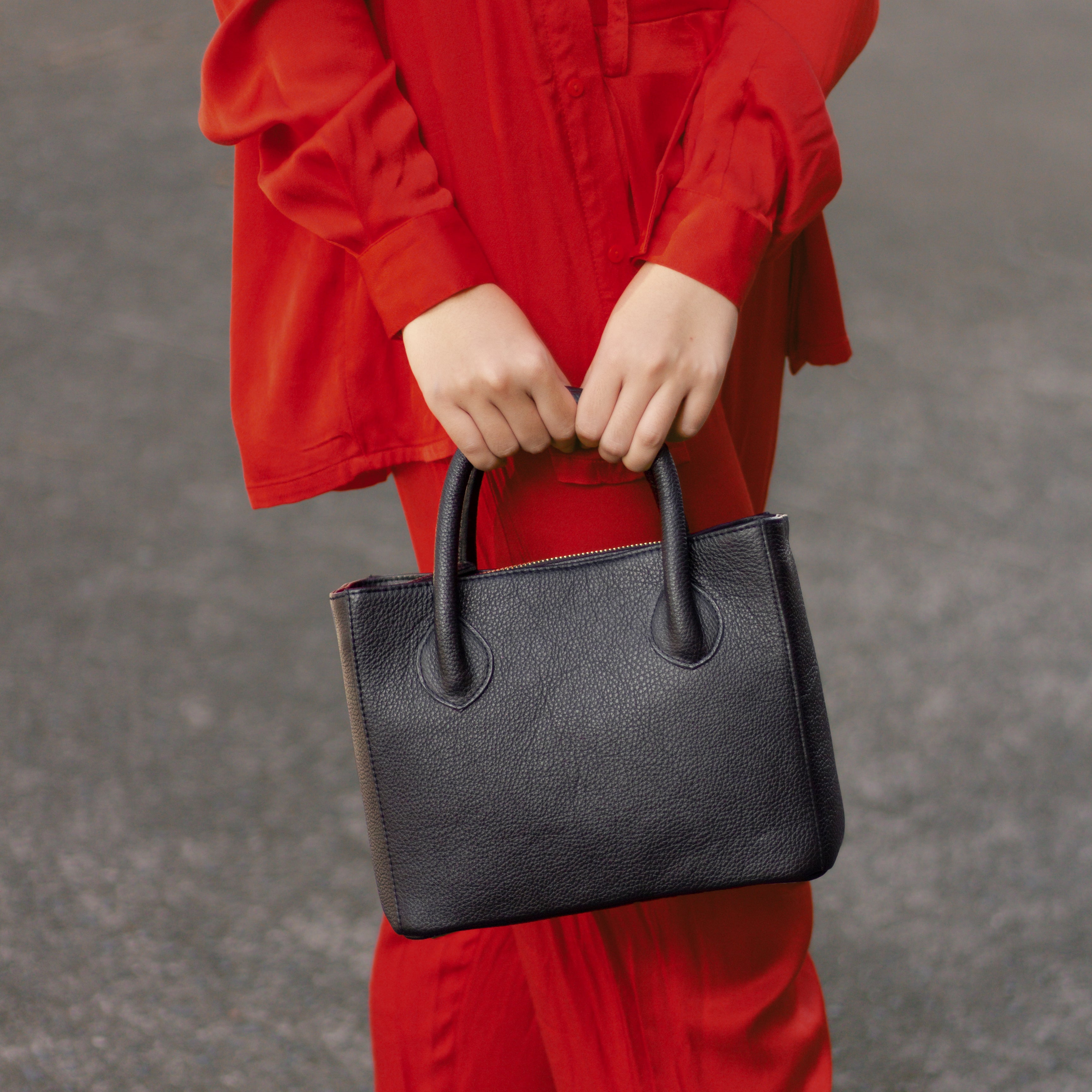 women in red outfit holding a milan square handbag in black