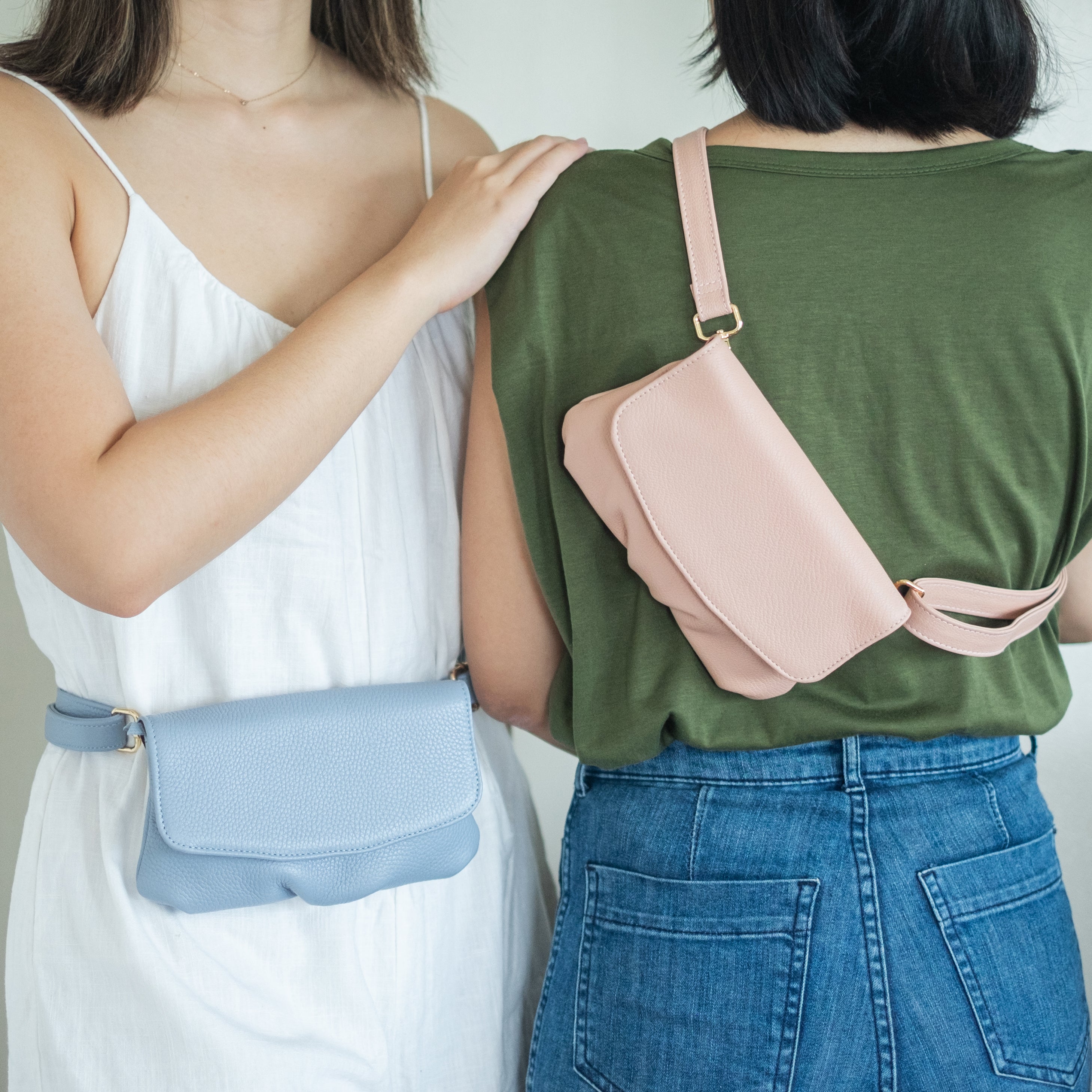 two women wearing a blue and light pink belt bags