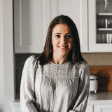 A woman is in a kitchen, and she is smiling.