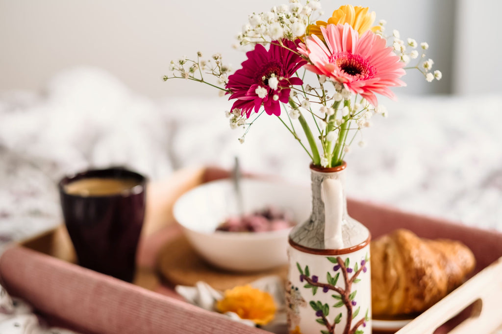 A tray with a vase of flowers and a cup of coffee
