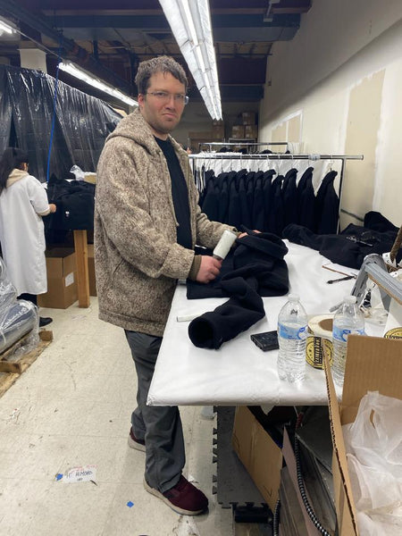 Alex, co-owner of WeatherWool, giving an Alex-smile while performing Quality Control Inspection on a WeatherWool ShirtJac at Better Team USA, where the tailoring was performed