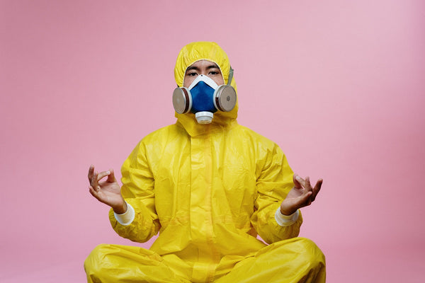Keine Corona-Panik dank Meditation - Mann im gelben Schutzanzug meditiert