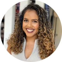 A person with curly hair smiling indoors.