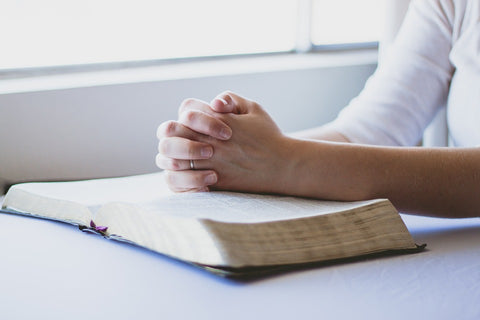 Woman's hands praying on top of the Holy Bible