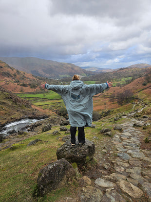 Woman holding her hands out at the lake district scenery