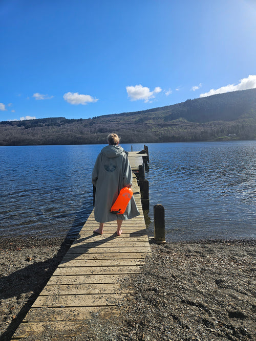 woman with a four seasons changing robe and toe float standing infront of a lake in the Lake District