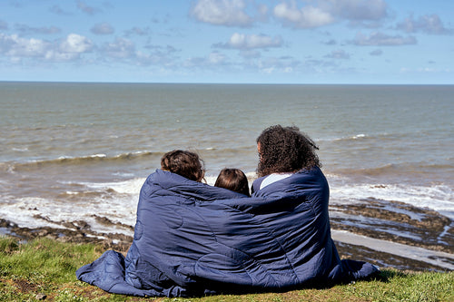 Family sat watching the waves in a blanket