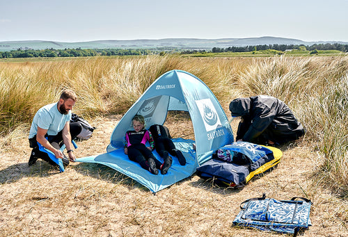 Family pitching a tent on the beach