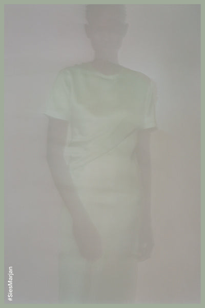 Blurry image of model wearing Sies Marjan Waverly Silk Twist Dress in Sage Green color. Shot by Theo Wenner.