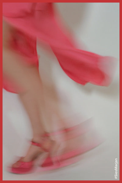 Blurry image of model walking wearing Sies Marjan Ellie Satin Strappy Sandal in red color. Shot by Theo Wenner.