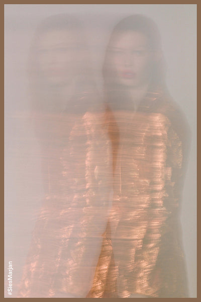 Blurry image of model wearing Sies Marjan Terry Metallic Belted Blazer in Pumpkin color. Shot by Theo Wenner.