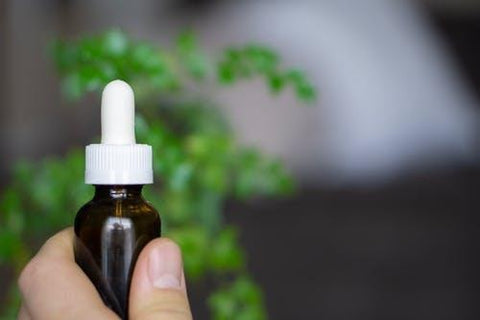 Person Holding White and Brown CBD Bottle