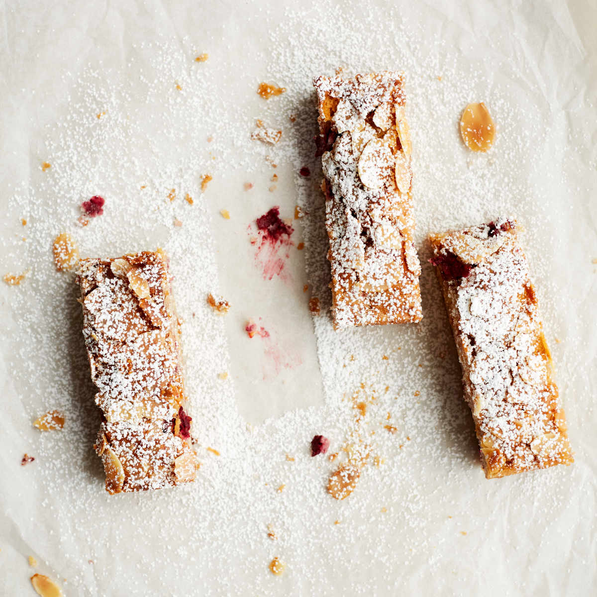 Portions of Exploding Bakery Raspberry & White Chocolate Bakewell decorated with icing sugar. 