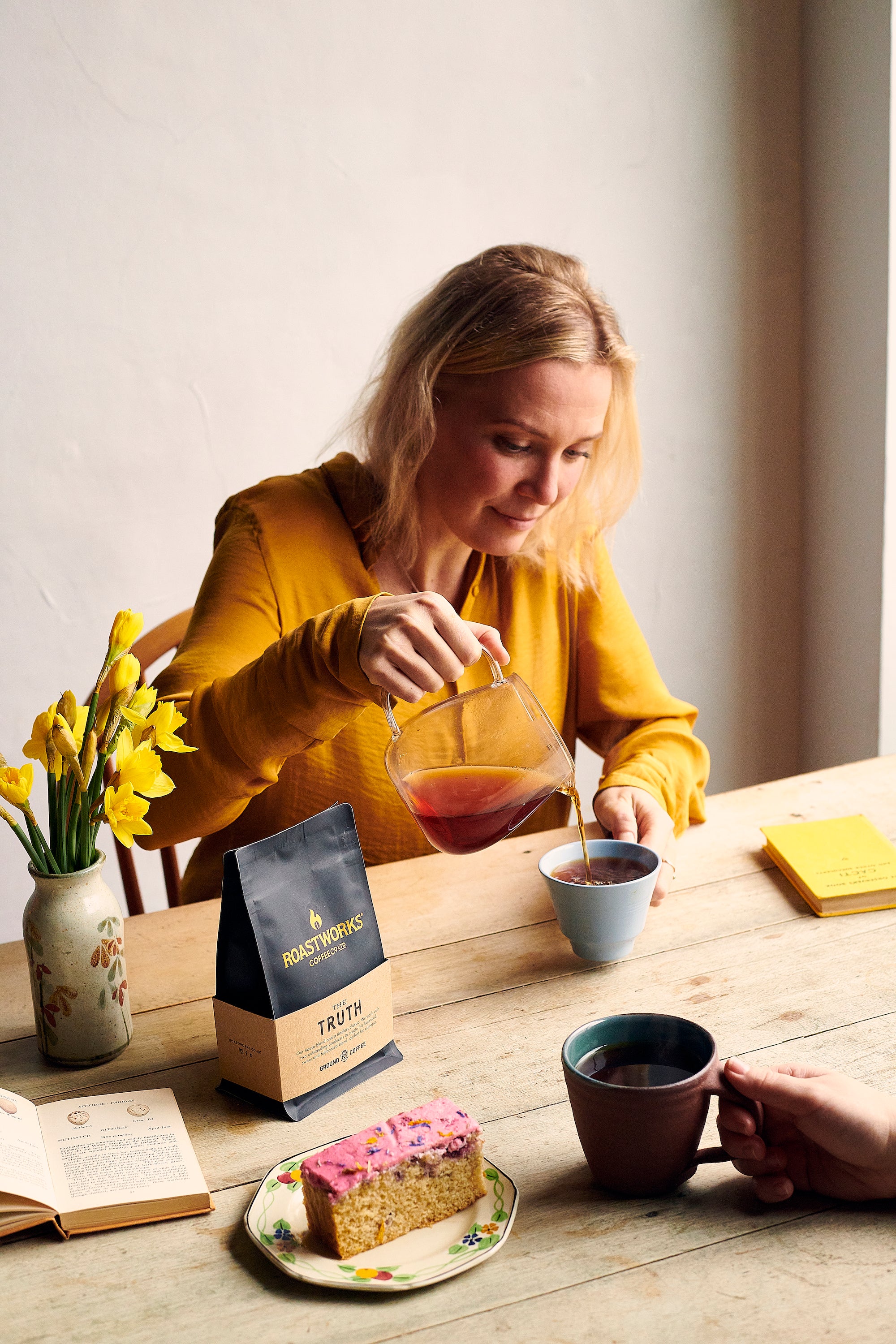 Someone Pouring A Cup Of Roastworks Coffee With A Slice of Berry Citrus Cake