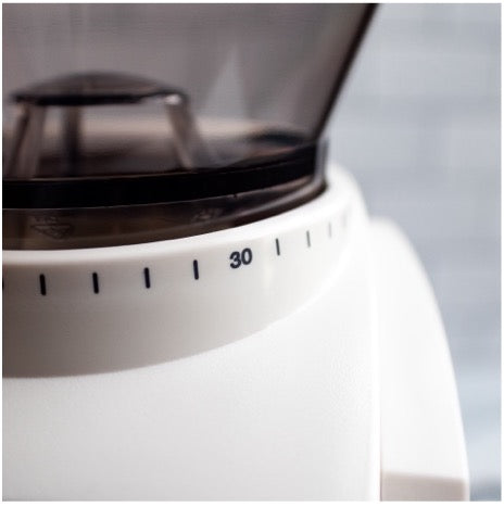 Close up of white burr coffee grinder featuring grind size selection