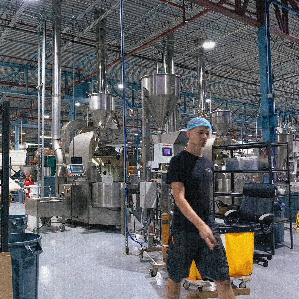 Human coffee roaster walking away from a line of non-human coffee roasters.