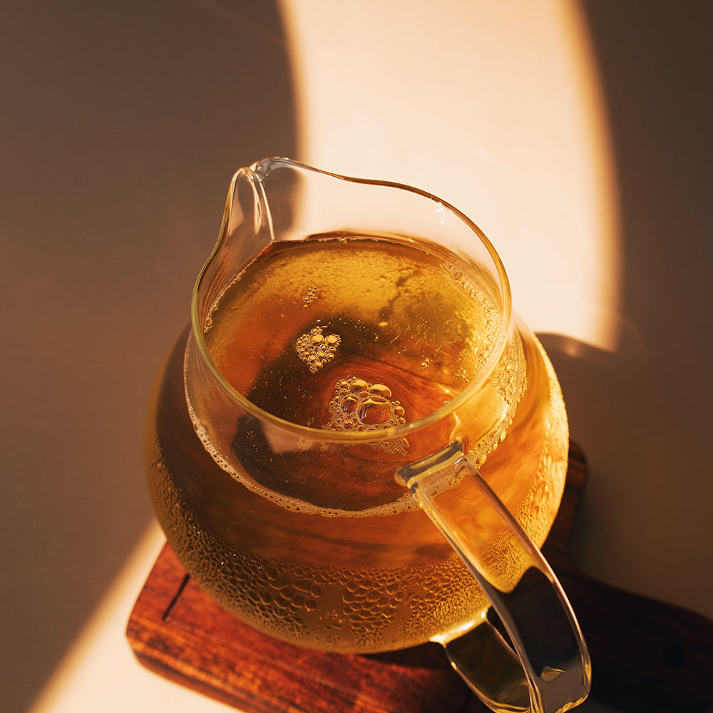 A pitcher of green tea on a wooden serving board.