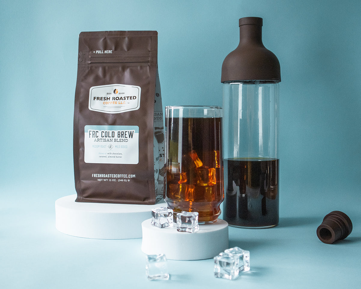 A glass of cold brew, a cold brewer, and a bag of cold brew coffee on a blue background.