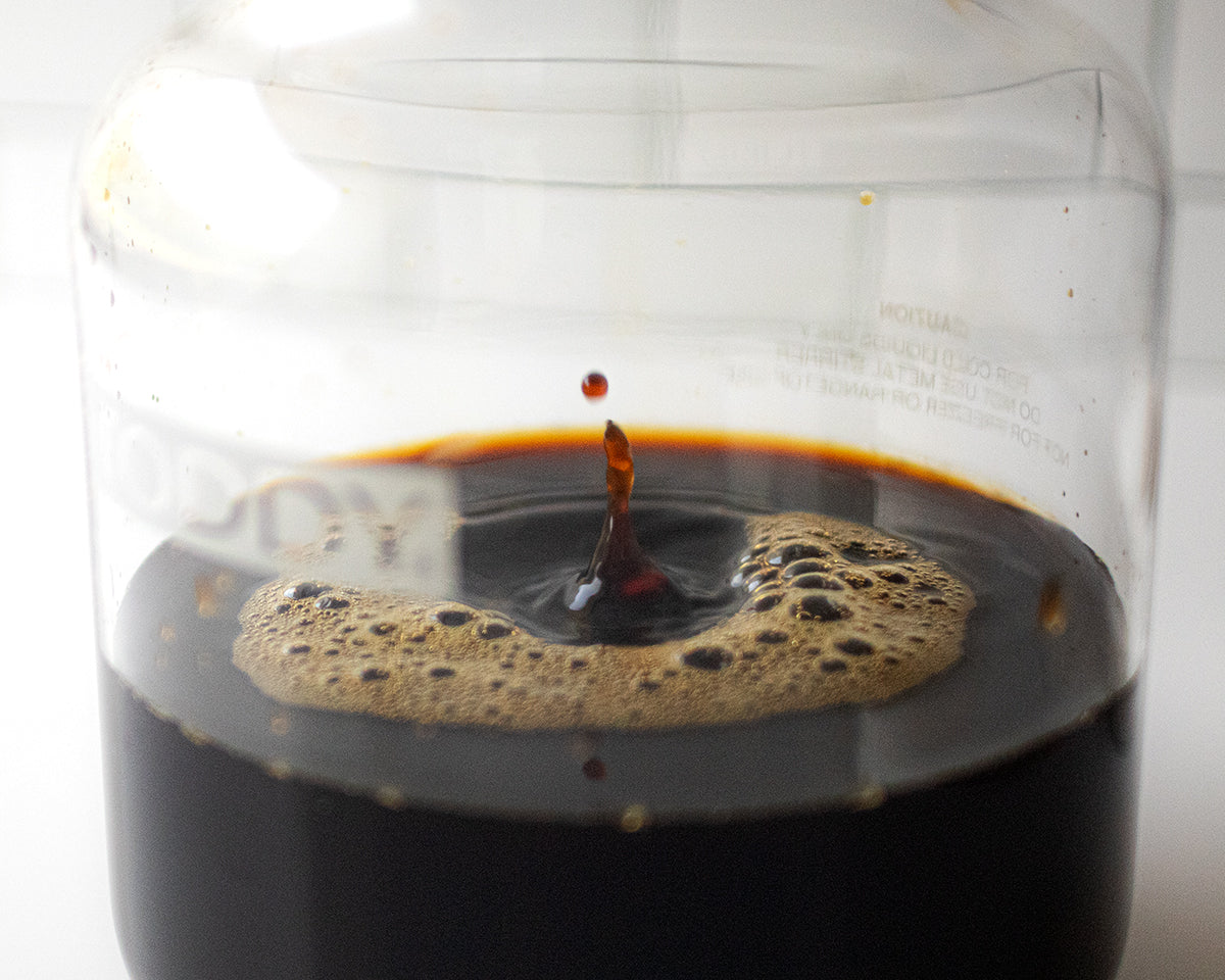 Cold brew concentrate drips into a Toddy Consumer glass carafe.