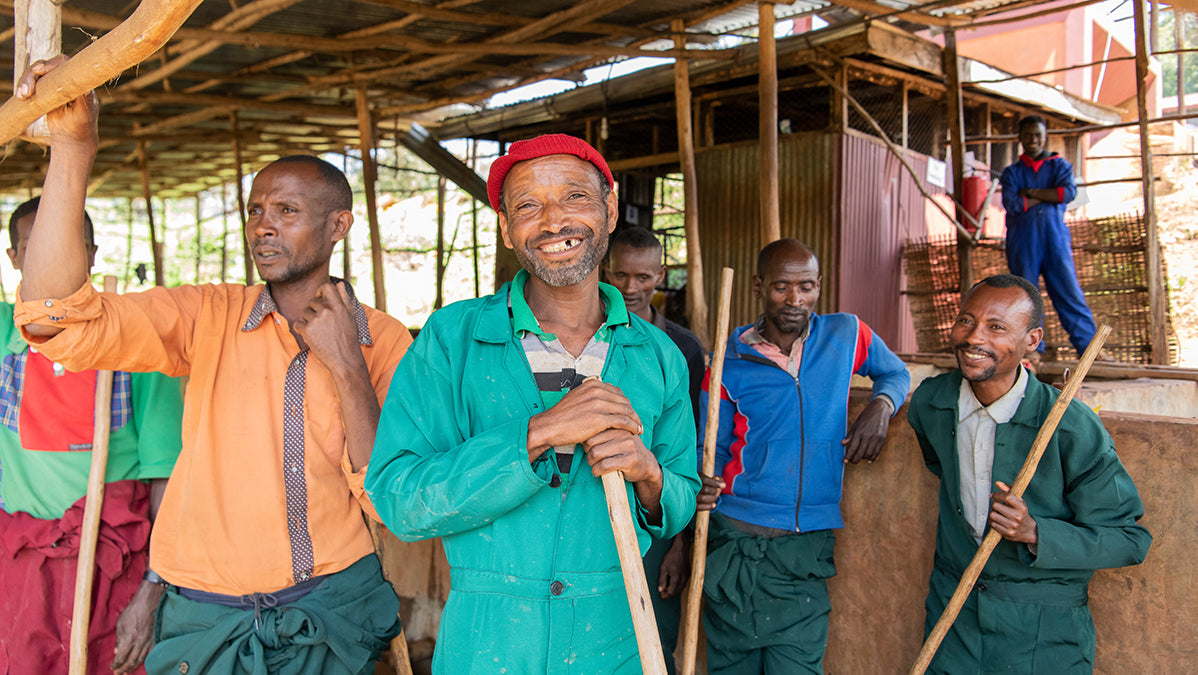 Coffee producers in Africa smiling at a processing mill.