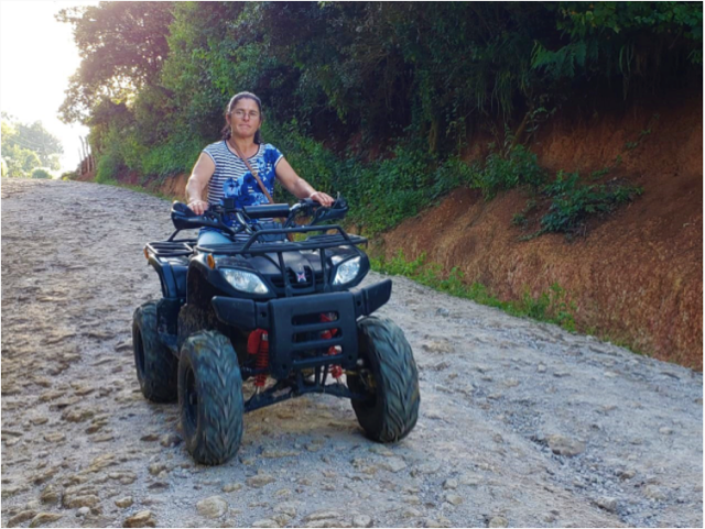 A Honduran coffee farmer rides a four-wheeler on a dirt road.