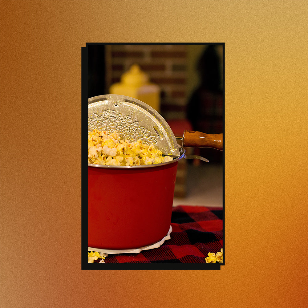 An image of a Whirley Pop stovetop popcorn popper on a mesh gradient background.