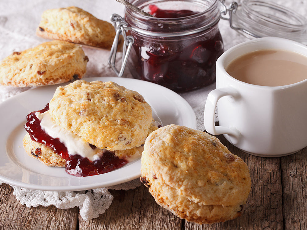 An image of biscuits, clotted cream, jam, and black tea.