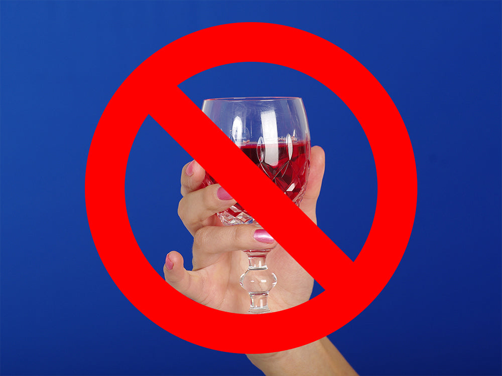 A bold red circle with a slash atop a photo of a woman sticking her pinky out while drinking wine.