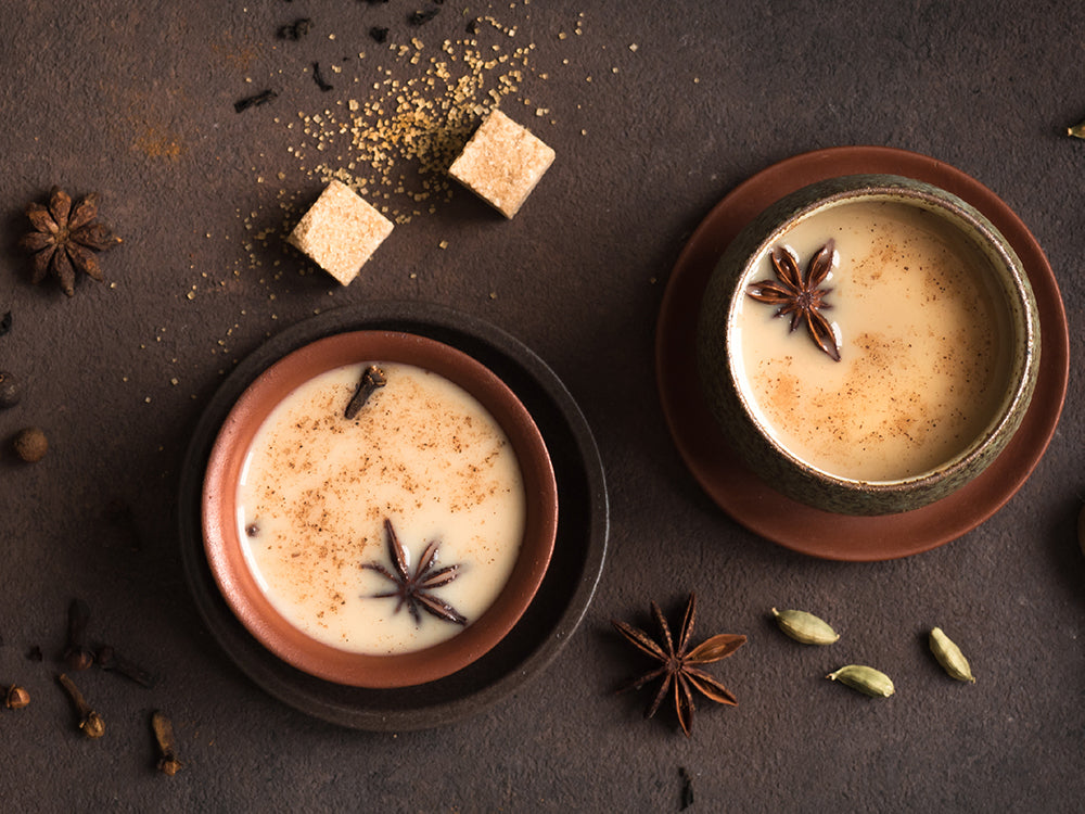 Cups of coffee with chai spices on a dark brown background.