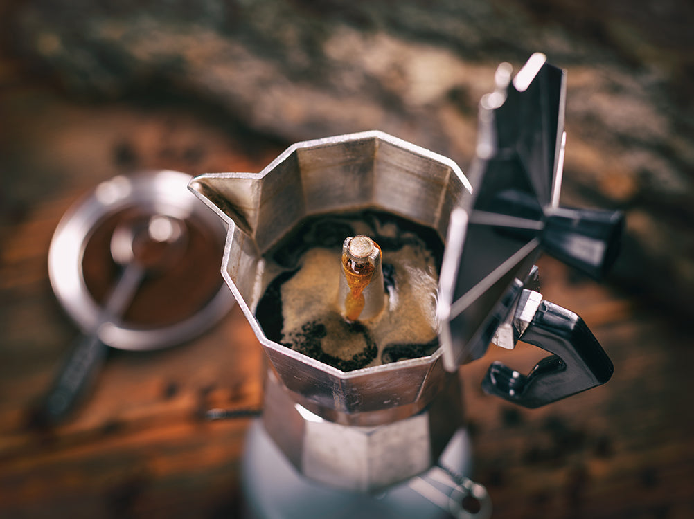 A top-down view of a moka pot brewing coffee.