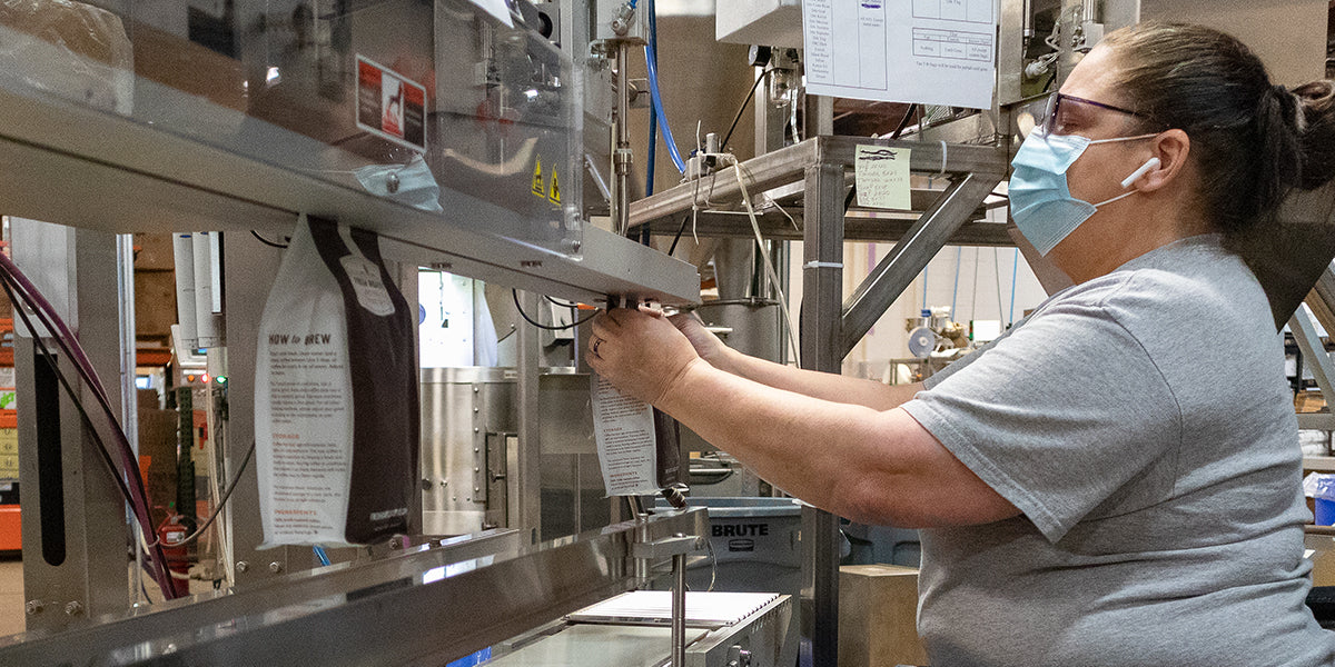 Bags of coffee being nitro flushed and band sealed to preserve freshness.