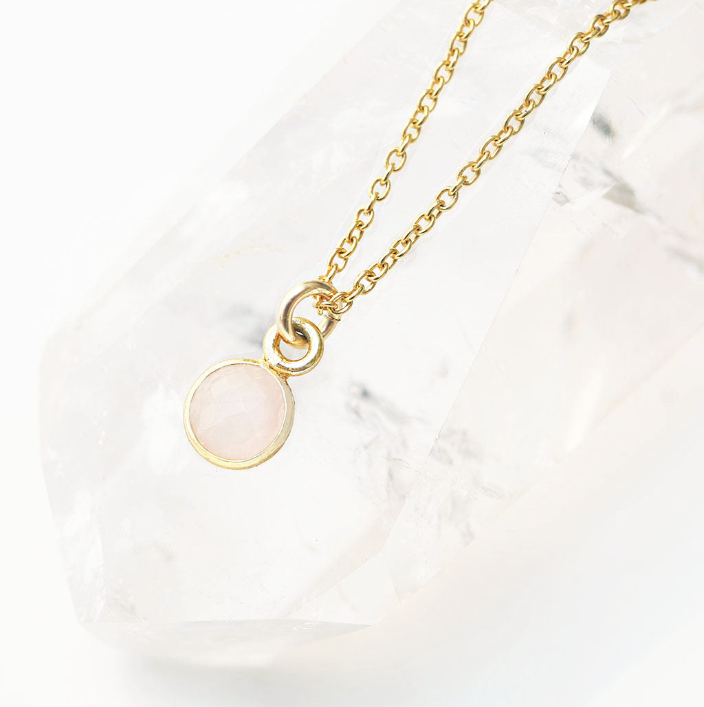 rose quartz circle pendant encased in gold strung on gold cable chain