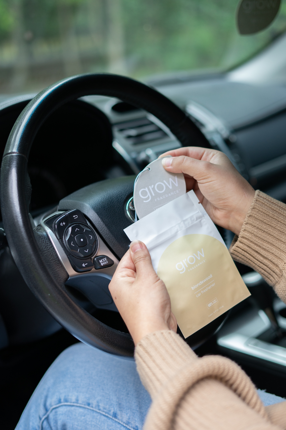 Enhance your driving experience with the natural allure of Grow Fragrance's Blondewood car freshener. Pictured in a driver's hand against the backdrop of a stylish car interior, this eco-friendly, plant-based scent offers a sustainable alternative to traditional car air fresheners. Ideal for the environmentally conscious driver, this non-toxic, vegan-friendly fragrance infuses your daily commute with a luxurious, subtle aroma that's as refreshing as it is responsible.