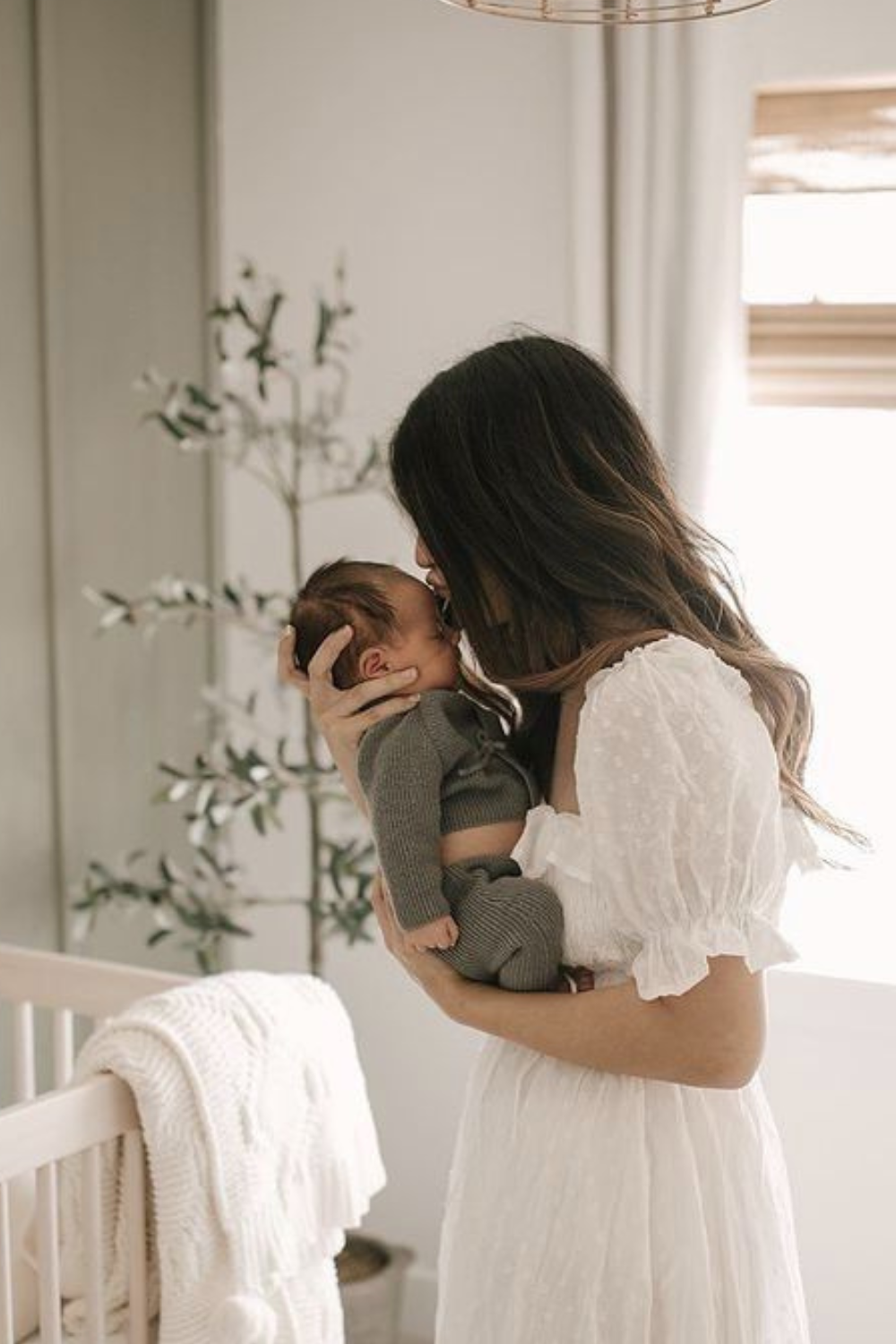 New mom lovingly cradles her newborn baby in a beautifully decorated nursery, illustrating the essence of crafting the perfect Postpartum Basket. Discover thoughtful gift ideas to support new mothers.