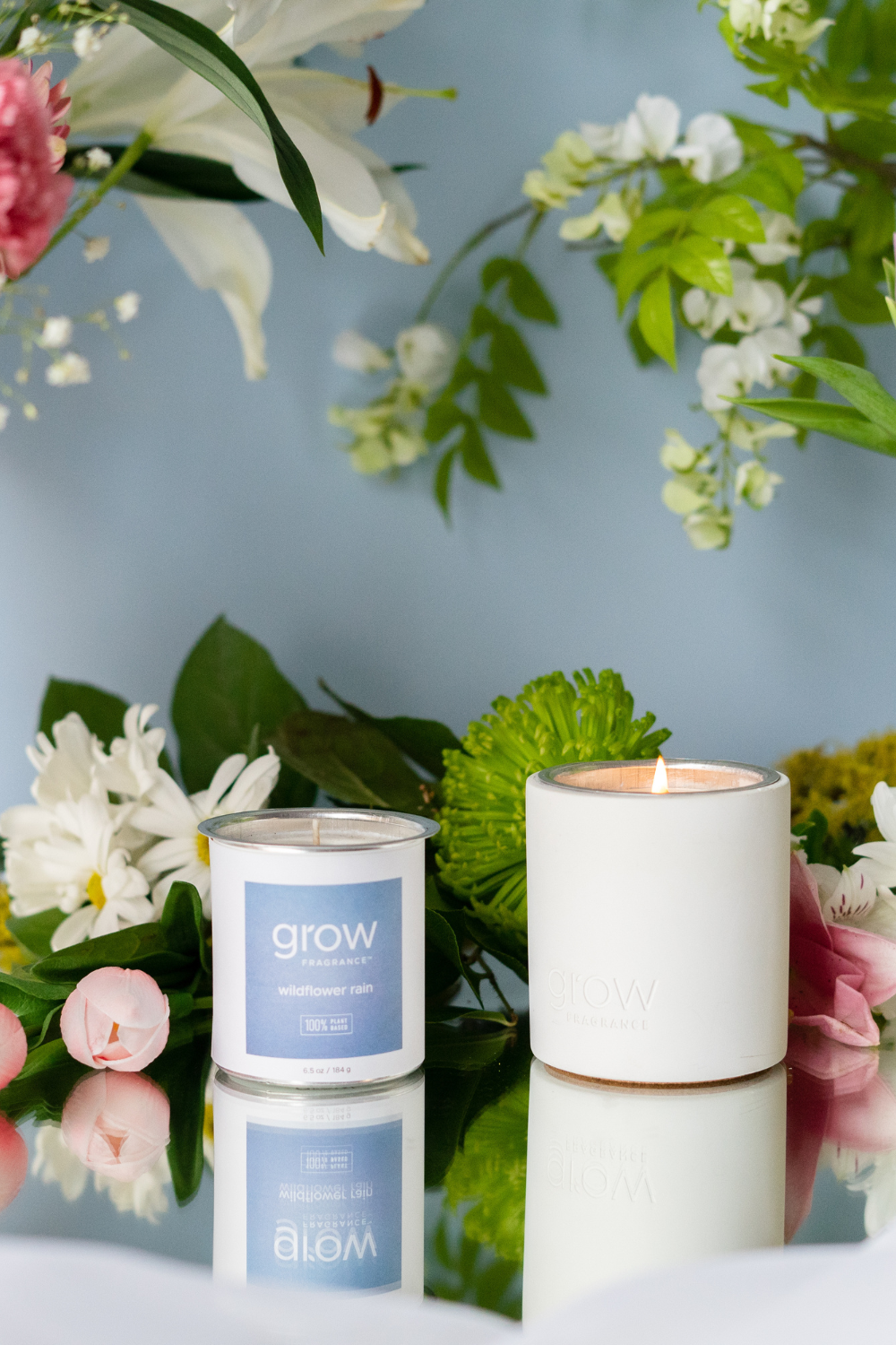 Wildflower Rain Candle in a Whimsical Forest Setting – A Glass Jar Candle with a Label Featuring Vibrant Wildflowers Amidst a Lush Rainforest. The Candle Emits a Refreshing Scent of Earthy Petrichor, Blooming Wildflowers, and Fresh Raindrops, Creating an Enchanting Atmosphere