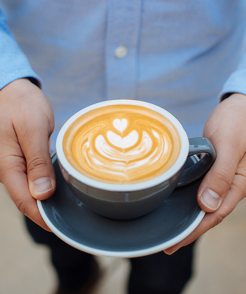 Seasoned barista showing off latte art tulip design.